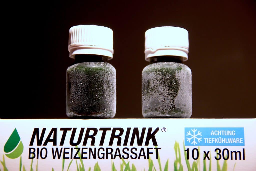 Naturtrink Weizengrassaft gefroren Fläschchen dunkler Hintergrund